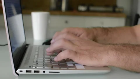 Close-up of man's hands typing on a laptop keyboard at a desk in a home office. Stockbeeldmateriaal 145465493