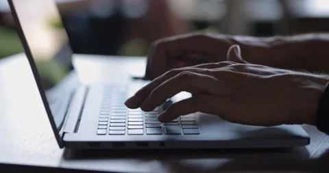 Close up of man's hands typing on laptop keyboard while sitting at table Stock Footage 164257874
