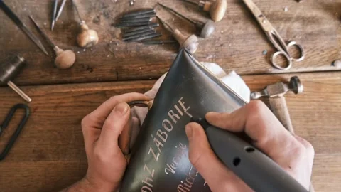 Close-up of a man's hands using an electric engraving tool. Creating artisan Vidéo 232004314