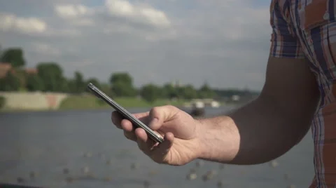 Close up of man`s hands using smartphone by the river 動画素材 52697376