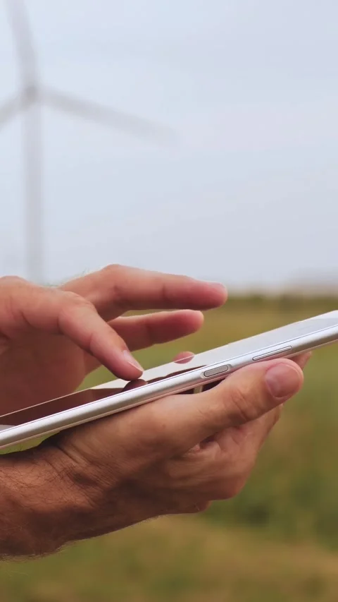 Close-up of man's hands using tablet outdoors with wind turbines in background Stock Footage 343562684
