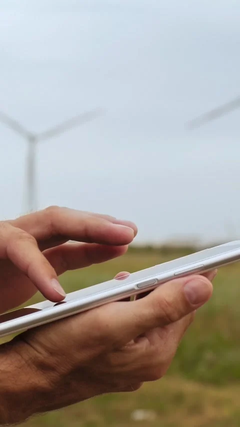 Close-up of man's hands using tablet near wind turbines. Digital technology and Stock Footage 343562741