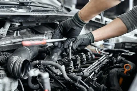 Close up of man's hands using wrench to remove spark plugs Stock Photos