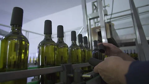 Close-up of a man's hands Wine Fit Caps On to Sealed Bottles On An Assembly Line Stock Footage 155424907