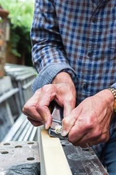 Close up of mans hands working with a plane on wooden plank Stock Photos