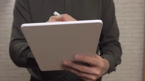 Close-up of a man's hands writing on the touch screen of a tablet using a stylus Stock Footage 165433191