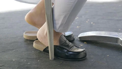 Close up of mans legs and bare feet win Italian loafer slippers at cafe Stock Footage 169467962