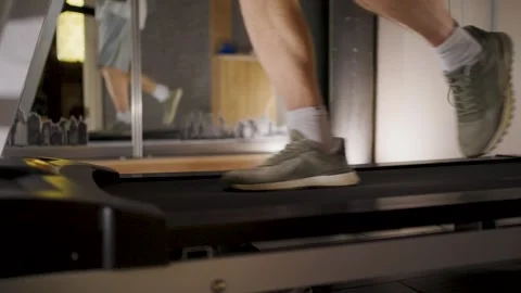 Close up of man's legs running on a treadmill in a gym. Low angle view of a.. Stock Footage 332054845