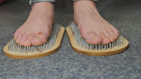 Close-up of a mans legs steps on a Sadhus board Stock-Footage 322197039