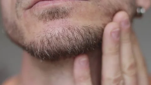 Close-up of a man's stubble. A young man is touching the beard stubble on his Stock Footage 231252418