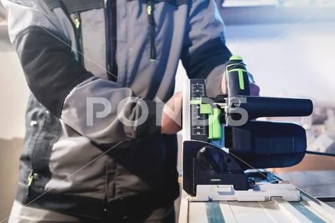 Close-up manual circular power saw in the hands of a worker in a home workshop Stock Photos