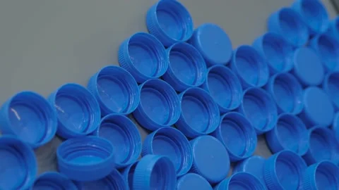Close up: many blue plastic bottle caps moving on conveyor belt, production line Vidéo 153796864