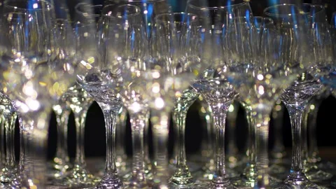 Close-up of many empty, clean wine glasses reflecting bright light on a dar.. Video stock 322121583