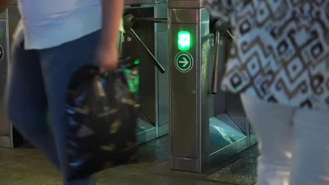 Close up of many people go through tripod turnstiles at night on the tram metro Stock Footage 250076505