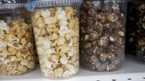 Close-up of many of plastic glasses with popcorn on a store shelf. Sweet chocola Stock Footage 274365193