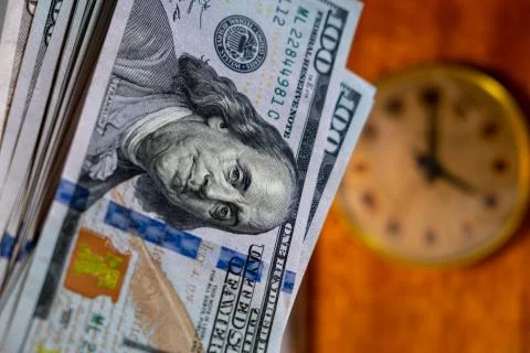 Close up of many US dollar banknotes with vintage clock. time is money concept 库存照片