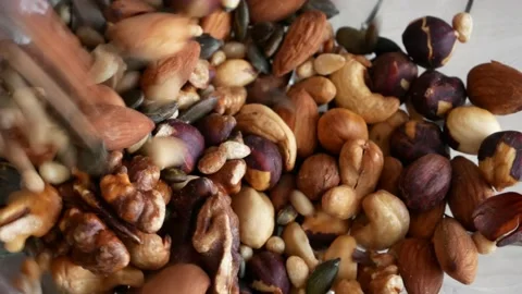Close-up of many various nuts falling into a glass bowl Stock Footage 146695334