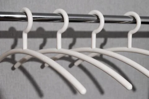 Close-up of many white plastic clothes hanger on rod with shadow Stock Photos