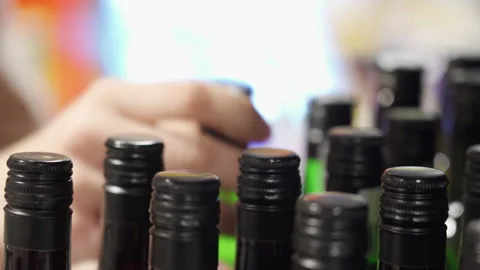 Close-up of many wine bottles on a store shelf, a woman's hand picking out one Stock Footage 211618921