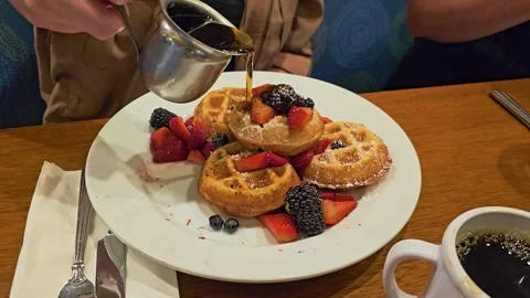 Close-up of maple syrup pouring over golden mini waffles with strawberries Stock Footage 340866647