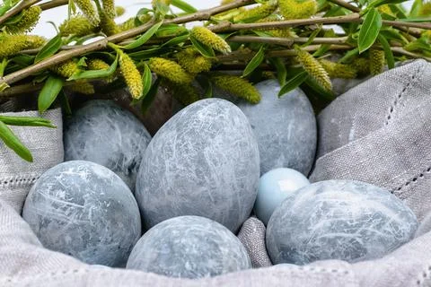 Close-up of marble-colored Easter eggs in a linen napkin and willow twigs. Stock Photos