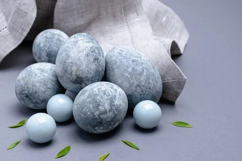 Close-up of marble-colored Easter eggs with green leaves and a napkin on a gr Stock Photos