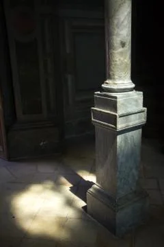 Close-up of a marble square column and a ray of sunshine in a dark room Stock Photos