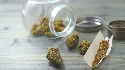 Close up of Marijuana joint essentials paper weed buds grinder and jar on woo Stock Footage 147163934