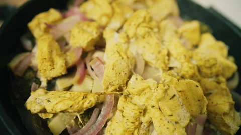 Close up of marinated chicken and vegetables cooking in a pan with spices and Stock Footage 345080444