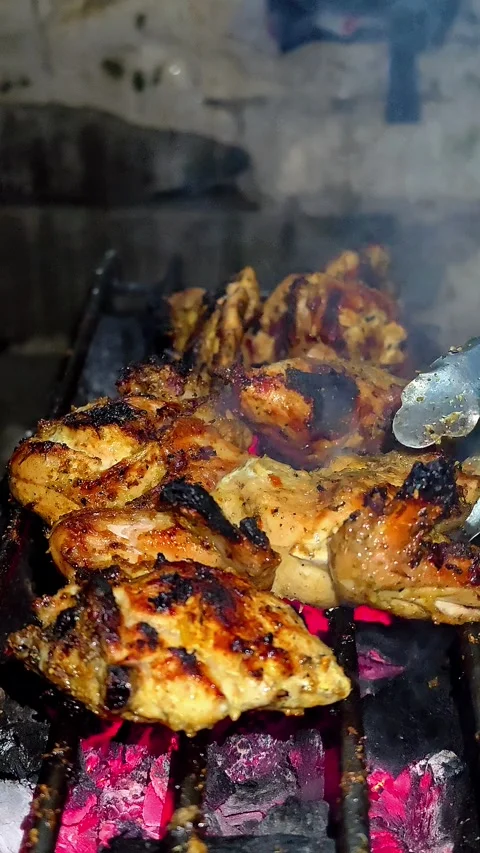 A close-up of marinated chicken pieces grilled over glowing embers.4K Vídeos de archivo 339044126