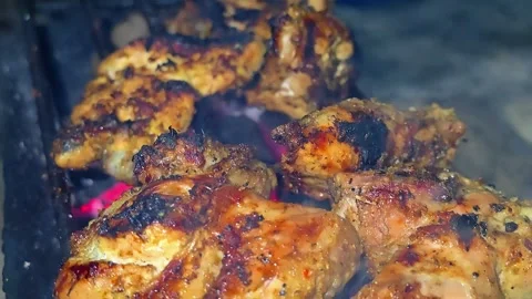 A close-up of marinated chicken pieces grilled over glowing embers.4K Vídeos de archivo 339044142