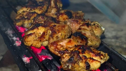 A close-up of marinated chicken pieces grilled over glowing embers.4K Vídeos de archivo 339044143