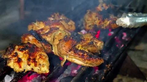 A close-up of marinated chicken pieces grilled over glowing embers.4K Vídeos de archivo 339044152