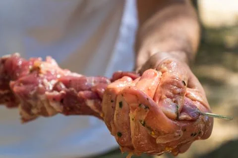 Close up of marinated meat being threaded onto barbecue skewer Fotos de archivo