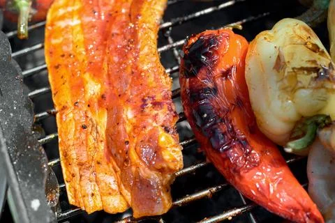 Close-up of marinated pork belly slice and roasted peppers grilling on barb.. Stock Photos