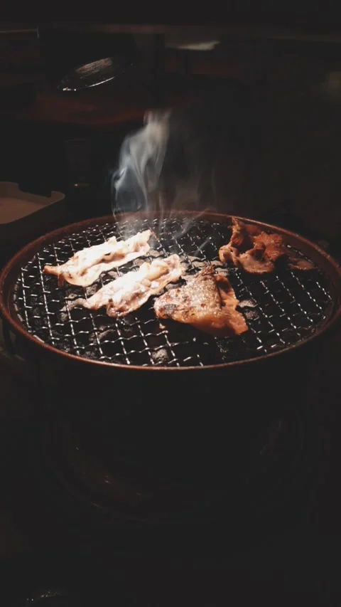 Close-up of marinated pork sizzling on a wire mesh gridiron over hot charcoal Stockbeeldmateriaal 344921846