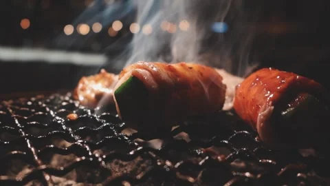 Close-up of marinated pork sizzling on a wire mesh gridiron over hot charcoal 스톡 동영상 344921876