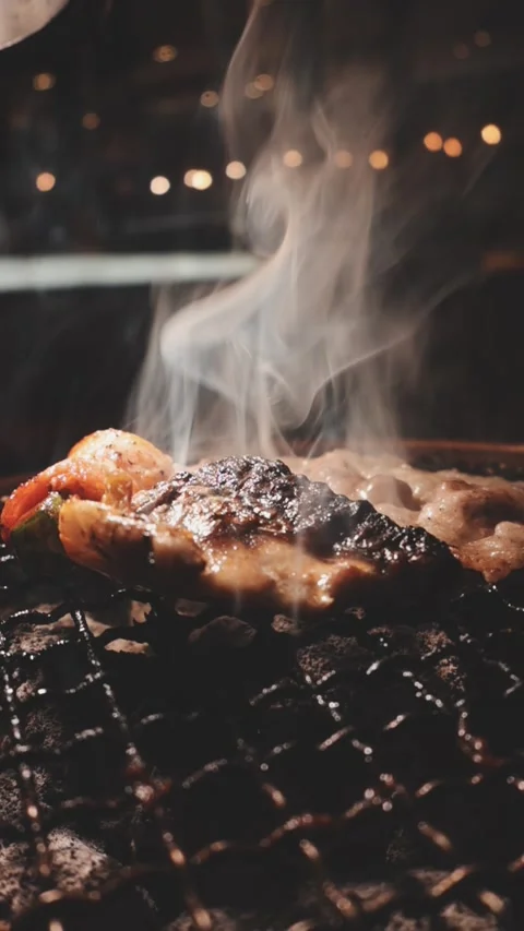 Close-up of marinated pork sizzling on a wire mesh gridiron over hot charcoal 스톡 동영상 344921879