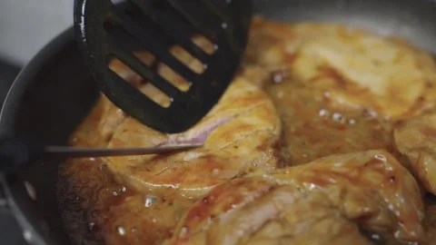 Close-up of marinated pork steaks cooking in savory sauce in a frying pan o.. Видео 340147900