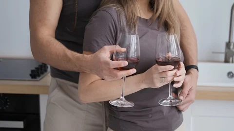 Close-up of married couple embracing each in kitchen, drinking red wine, 4k Stock Footage 128112101