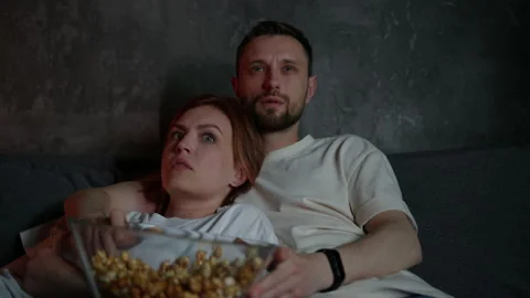 Close-up of a married couple lying on the couch and watching horror movies Stock Footage 197770922