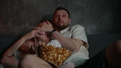 Close-up of a married couple lying on the couch and watching horror movies Stock Footage 220562442