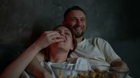 Close-up of a married couple lying on the couch and watching a movie Stock Footage 220564302