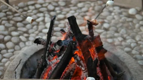 Close up of marshmallows roasting on a sticks over a flaming fire. Leisure at Stock Footage 159452528