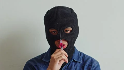 Close up of masked kidnapper or criminal holding medical syringe against white Stock Footage 333613565