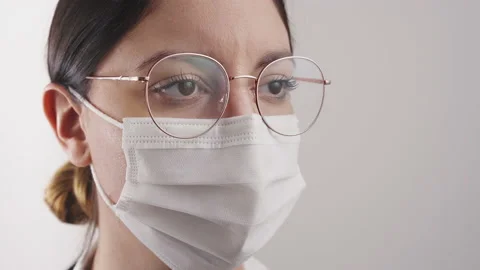 Close-up of a masked woman with studio lighting. She turns her eyes to the ca Stock Footage 148349634