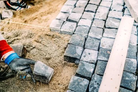 Close up of mason hands using granite stones to create pavement Stock Photos