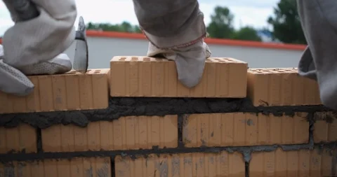 Close-up of masonry in which two builders stack last bricks, cover with mortar Stock Footage 116794858