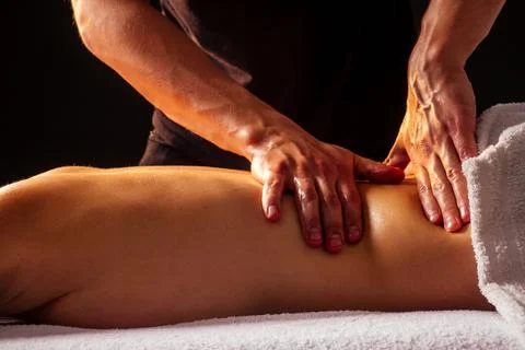 Close-up masseur hands doing back massage to female client in spa center Stock Photos