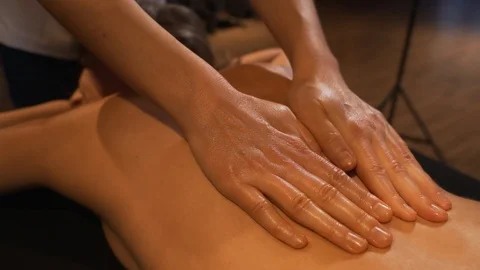 Close-up masseur hands doing spin massage. The girl lying on the table of the Stock Footage 122148734